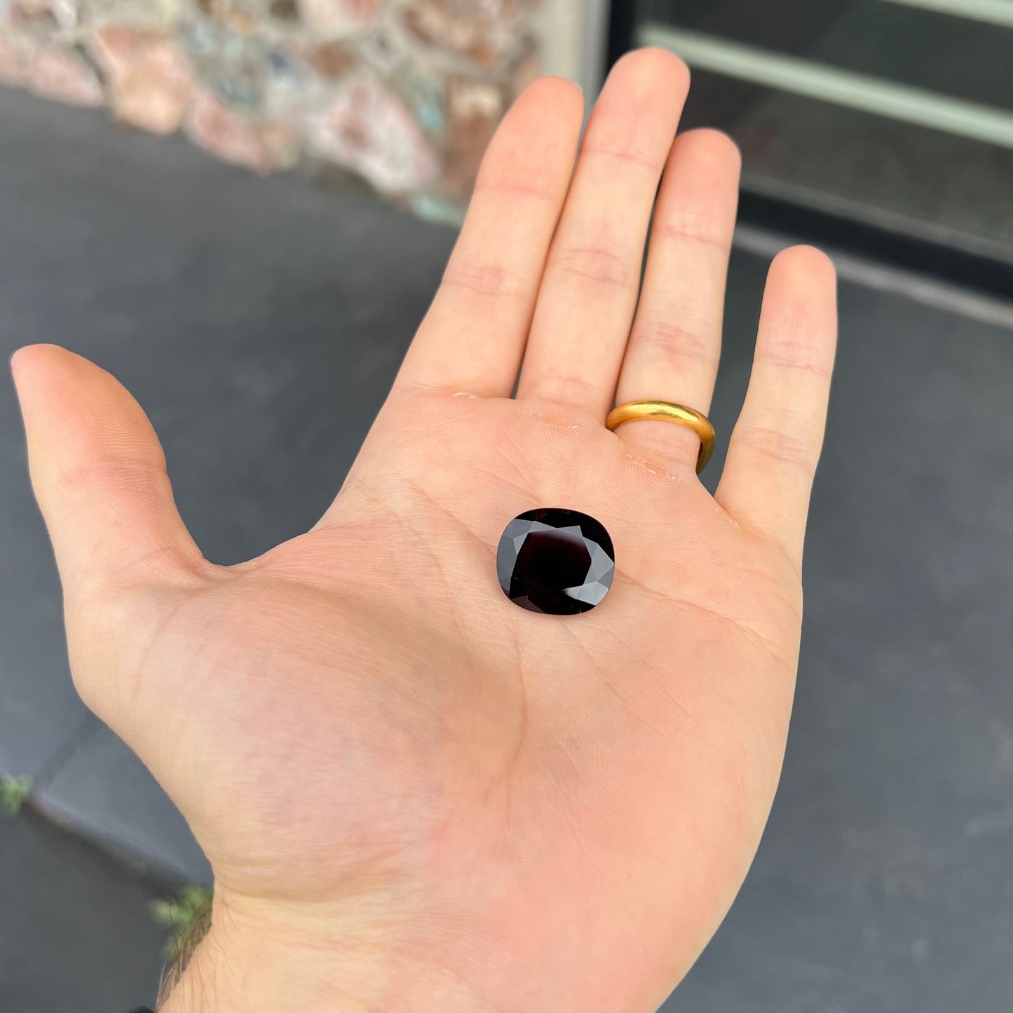 A loose, faceted oval cut rubellite tourmaline gemstone.  The stone is a dark purple red color.