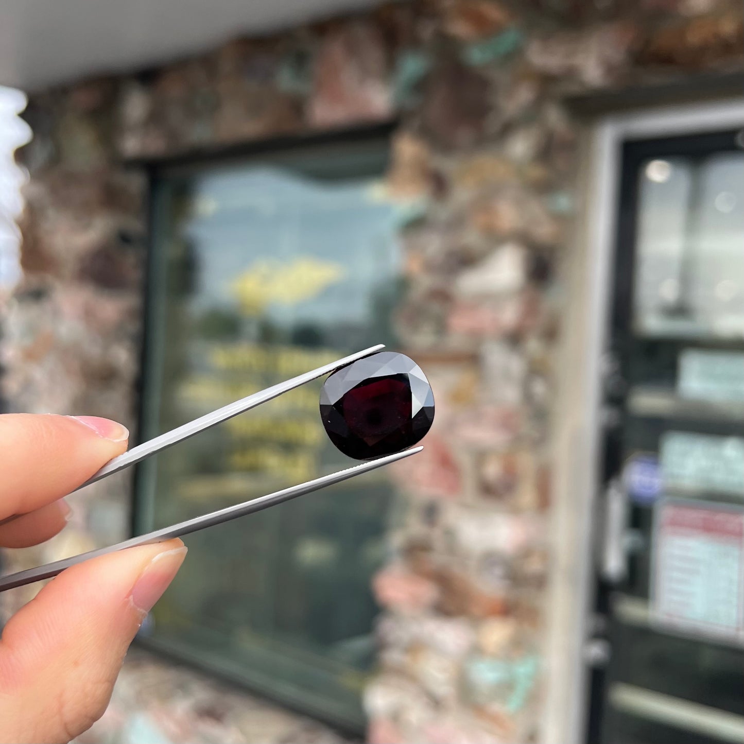 A loose, faceted oval cut rubellite tourmaline gemstone.  The stone is a dark purple red color.