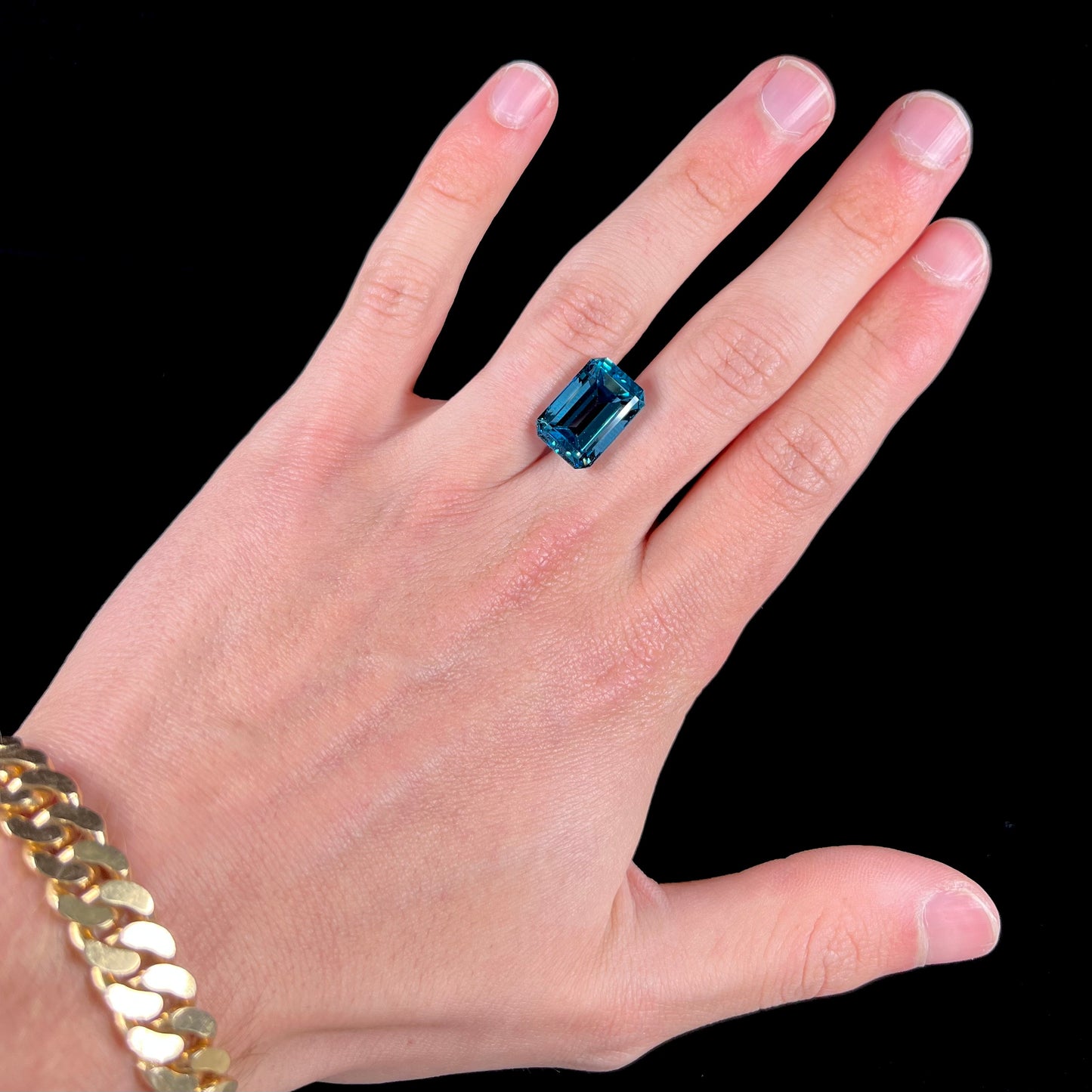 A loose, emerald cut London blue topaz gemstone.  The stone is a deep, dark blue color.