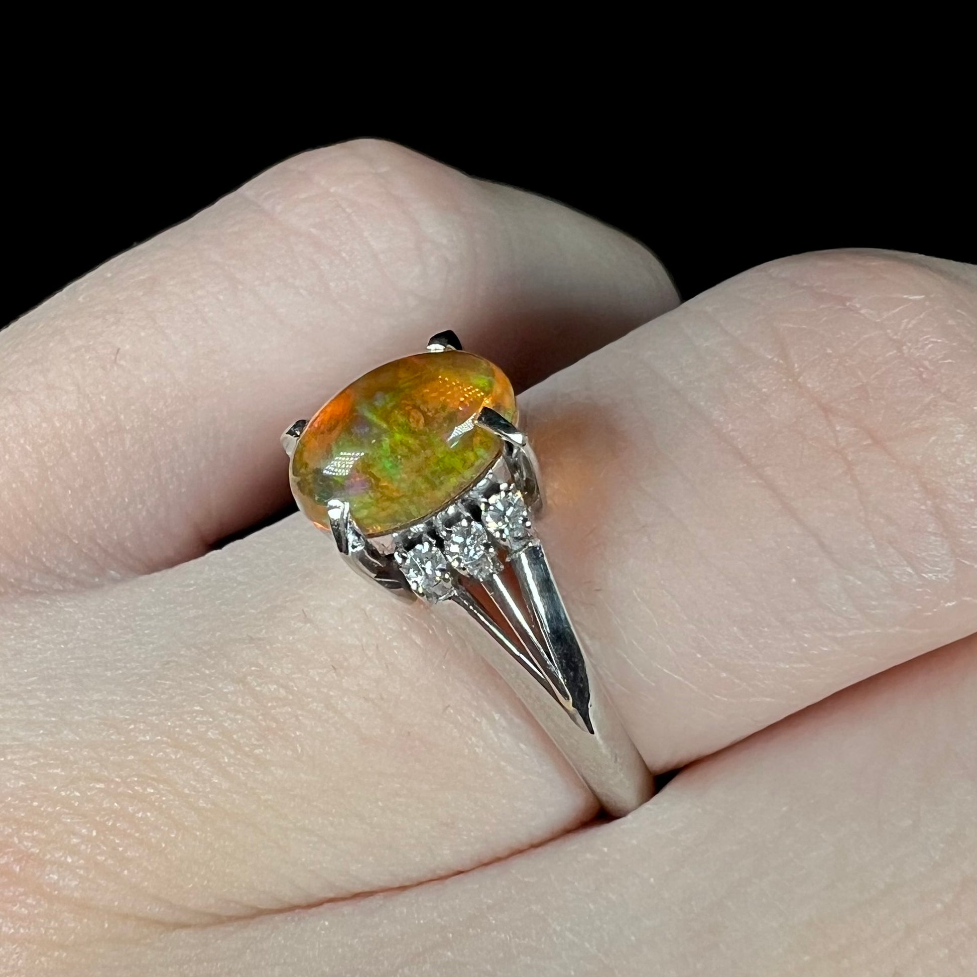 A platinum filigree and diamond-accented Mexican fire opal ring.  The opal is orange with green fire.