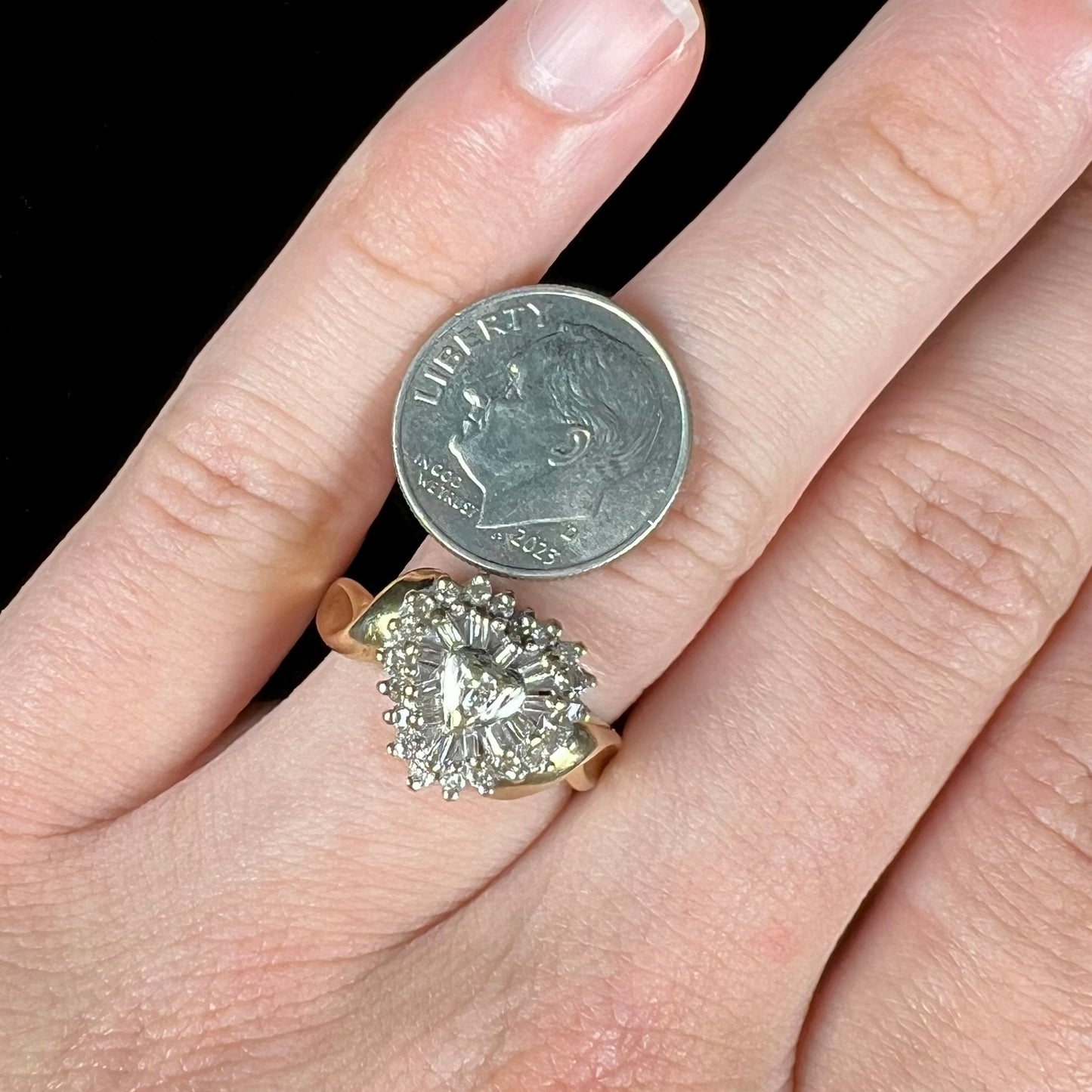 A ladies' heart shaped diamond cluster ring.  The ring is set with pear shaped, baguette cut, and round diamonds.