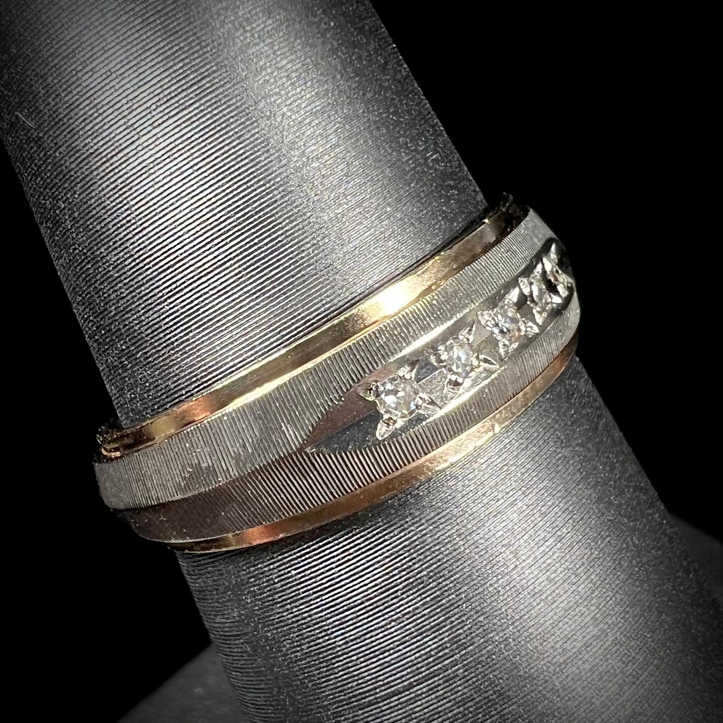 A unisex, two-tone white and yellow gold diamond wedding band.  The white gold is textured.