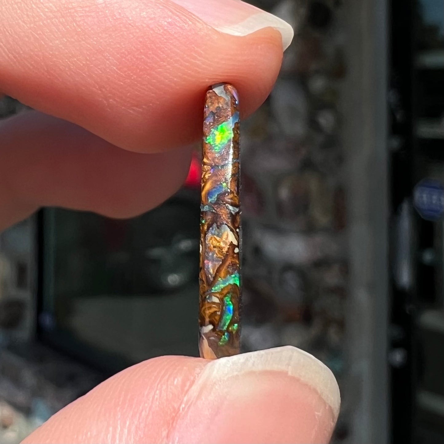 A loose, pear shaped boulder opal stone from Koroit, Australia that has vivd green and blue veins of color.