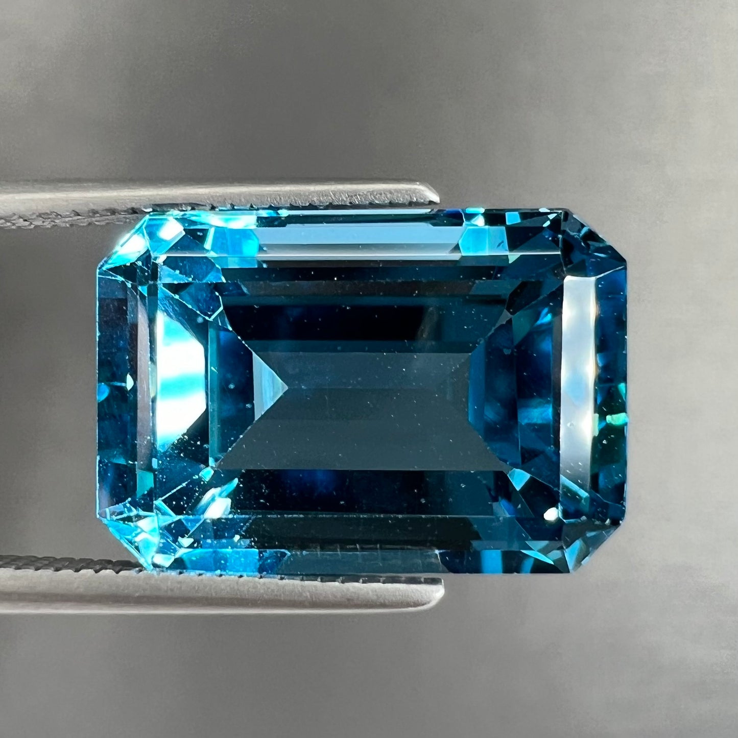 A loose, emerald cut London blue topaz gemstone.  The stone is a deep, dark blue color.