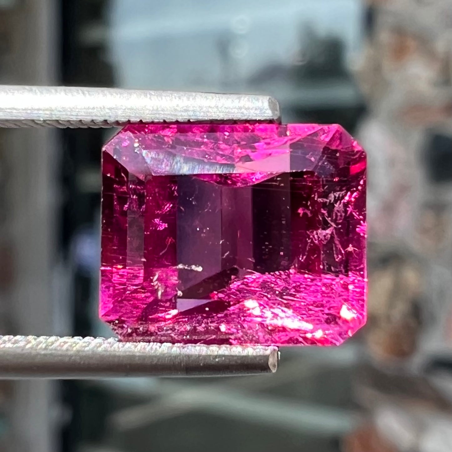 A loose, faceted modified emerald cut hot pink tourmaline stone.