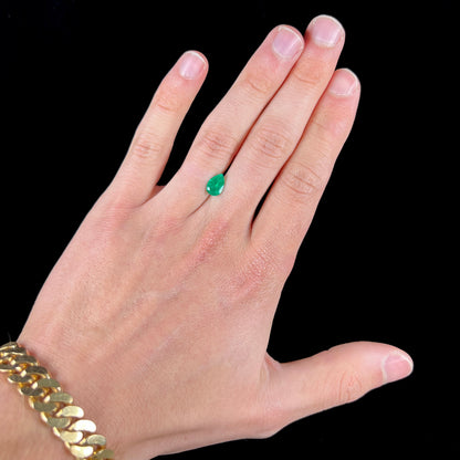 A loose, pear shaped natural emerald gemstone.