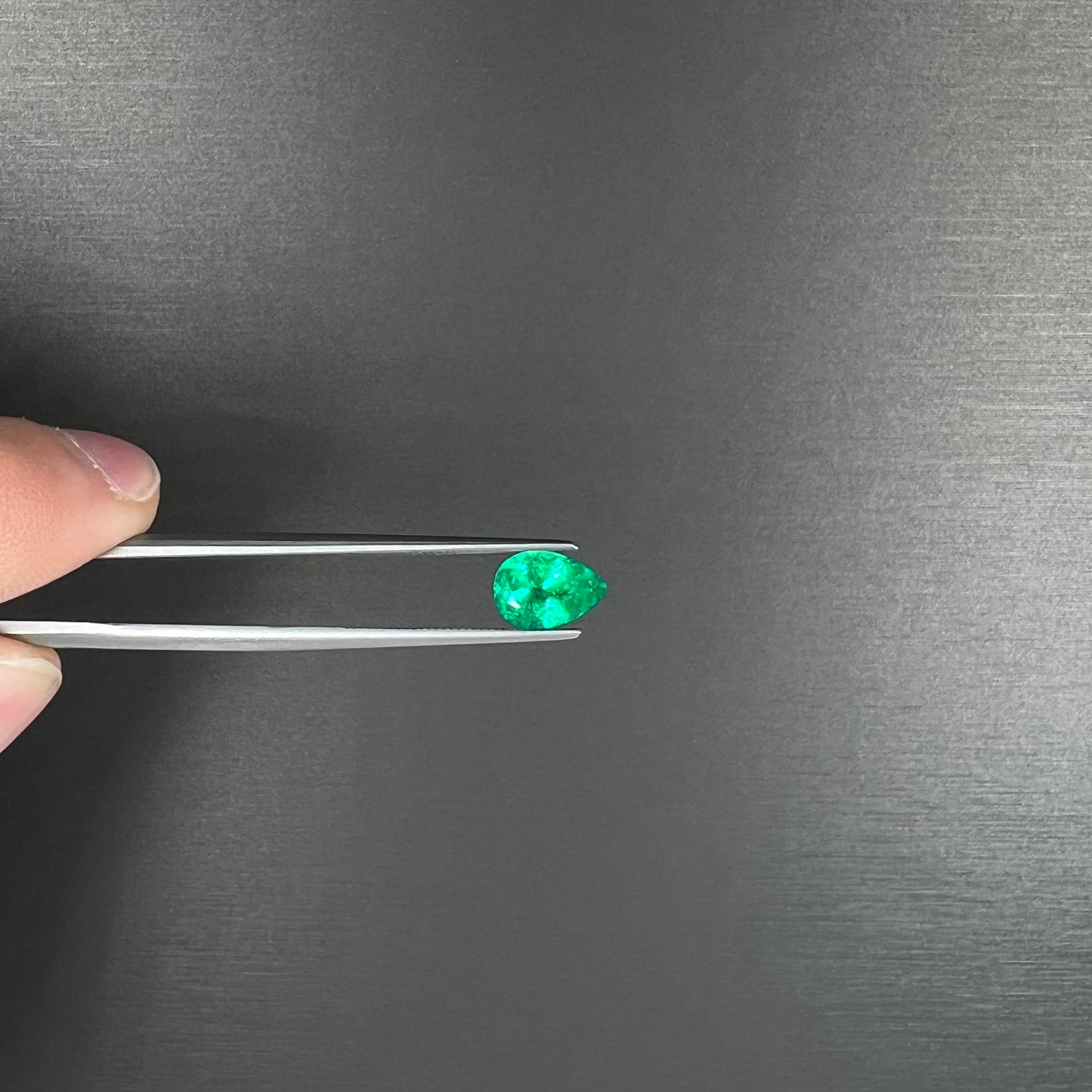 A loose, pear shaped natural emerald gemstone.