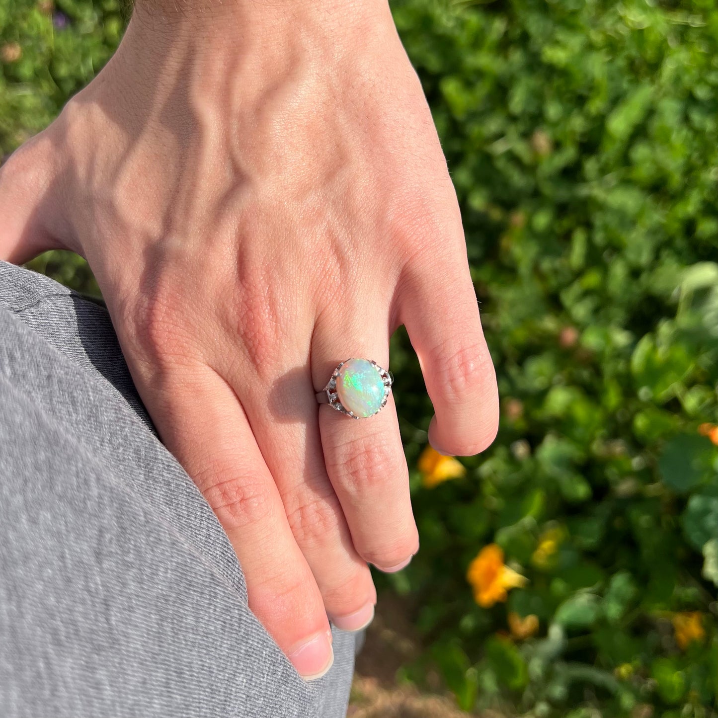 A ladies' Australian opal solitaire engagement ring mounted in platinum.  The opal has green and blue colors.