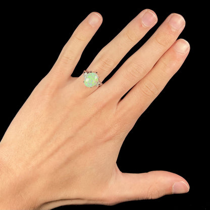 An Australian crystal opal and diamond engagement ring set in a platinum filigree mounting.  The opal plays green/blue colors and has a crack.