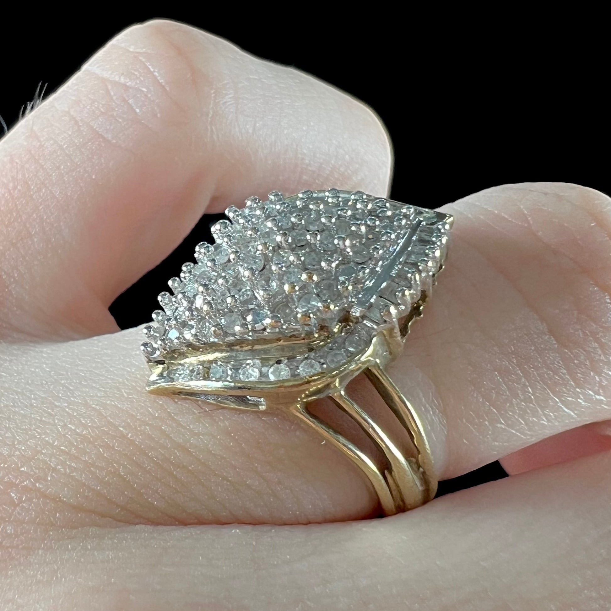 A ladies' yellow gold and diamond cluster ring.  The diamonds are round and baguette shaped, and the ring is navette shaped.