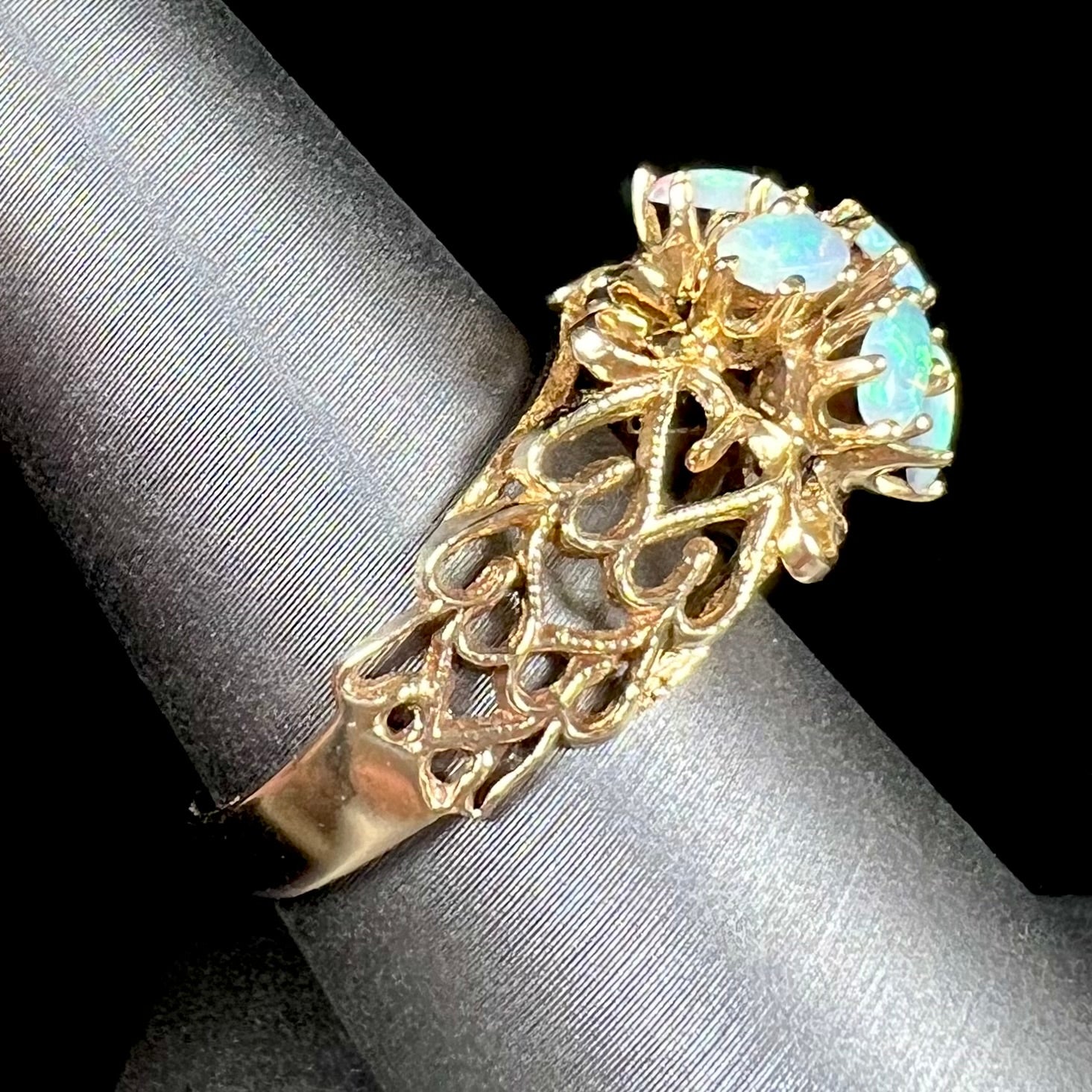 A vintage, 1950's style opal cluster ring cast in yellow gold with a heart shaped filigree design.