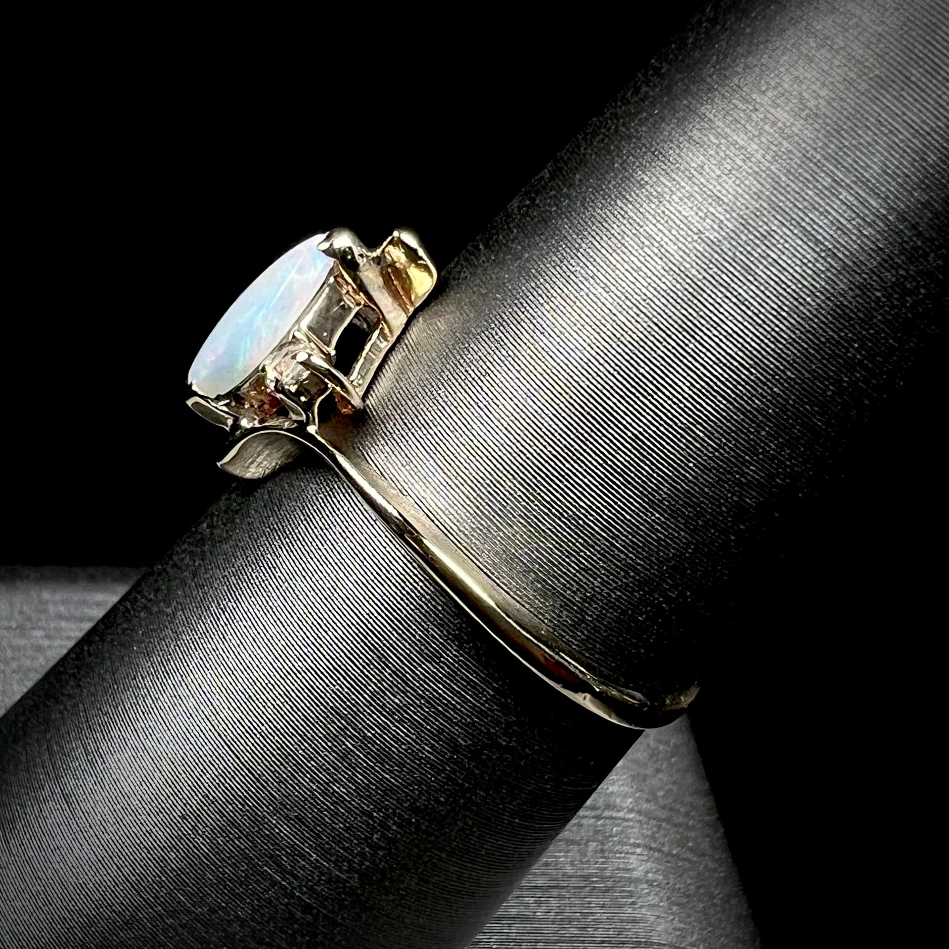 A yellow gold marquise cut opal ring set with two white sapphire accent stones.