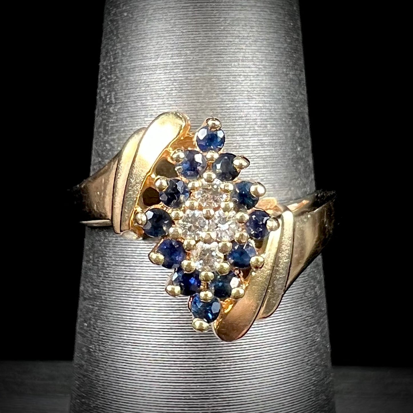 An estate, yellow gold ladies' cluster ring mounted with four round diamonds and twelve round blue sapphires.