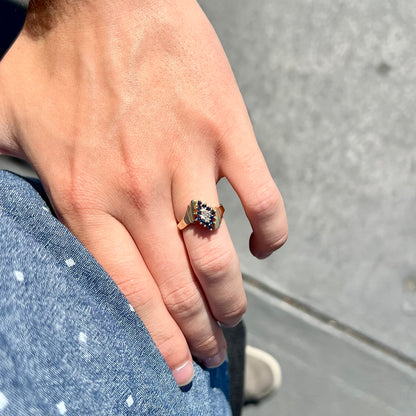 An estate, yellow gold ladies' cluster ring mounted with four round diamonds and twelve round blue sapphires.