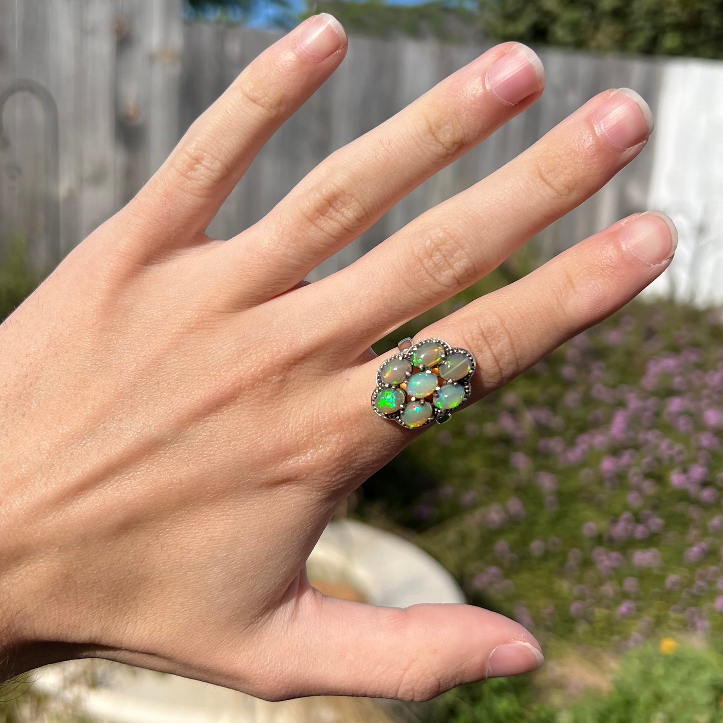 A sterling silver cluster ring prong-set with seven green Ethiopian fire opals.