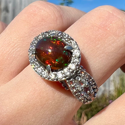 A CZ-accented sterling silver halo ring mounted with a smoked Ethiopian fire opal.  The opal plays green, red, and blue colors.