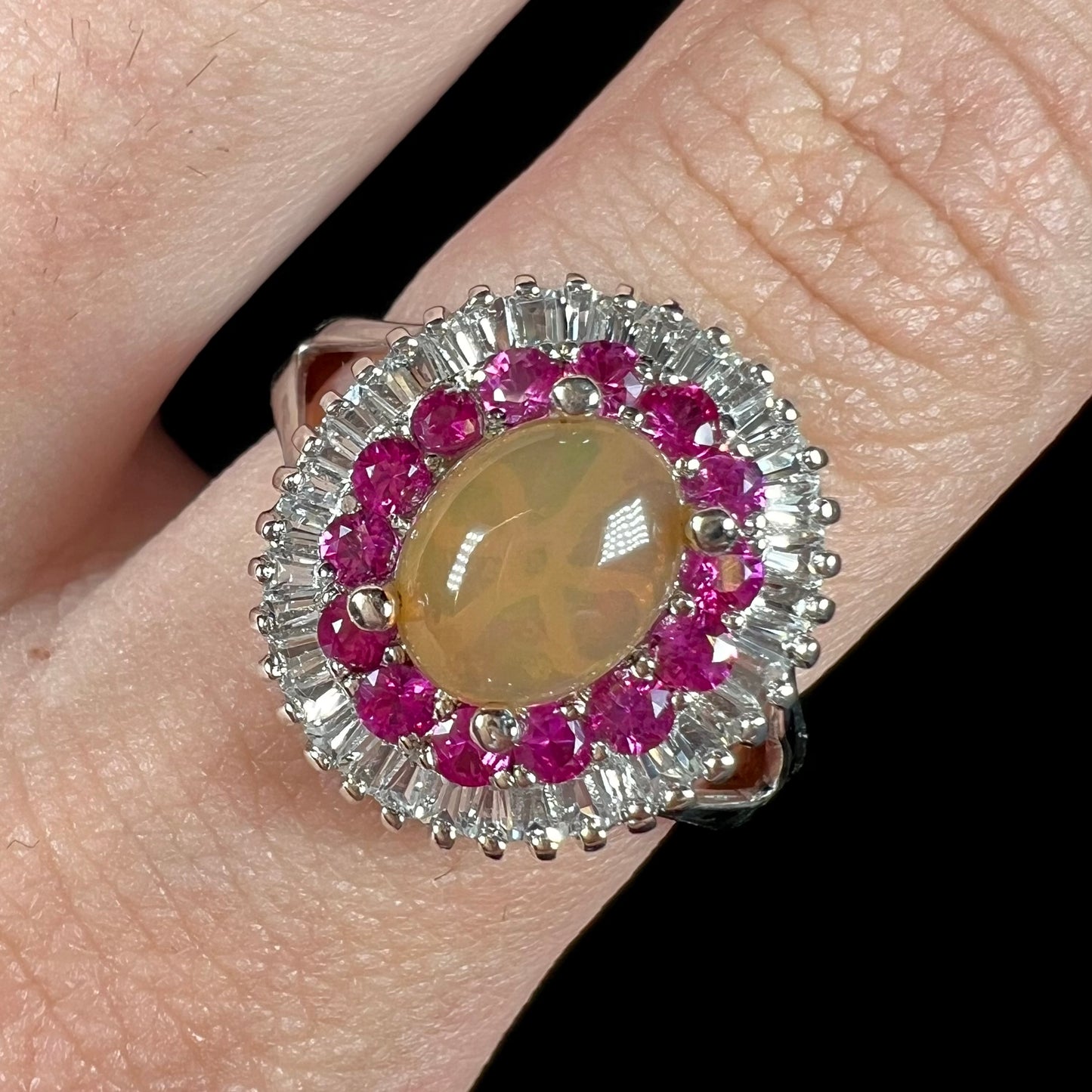 A sterling silver Ethiopian opal ring mounted with a halo of white CZs and another halo of synthetic pink sapphires.