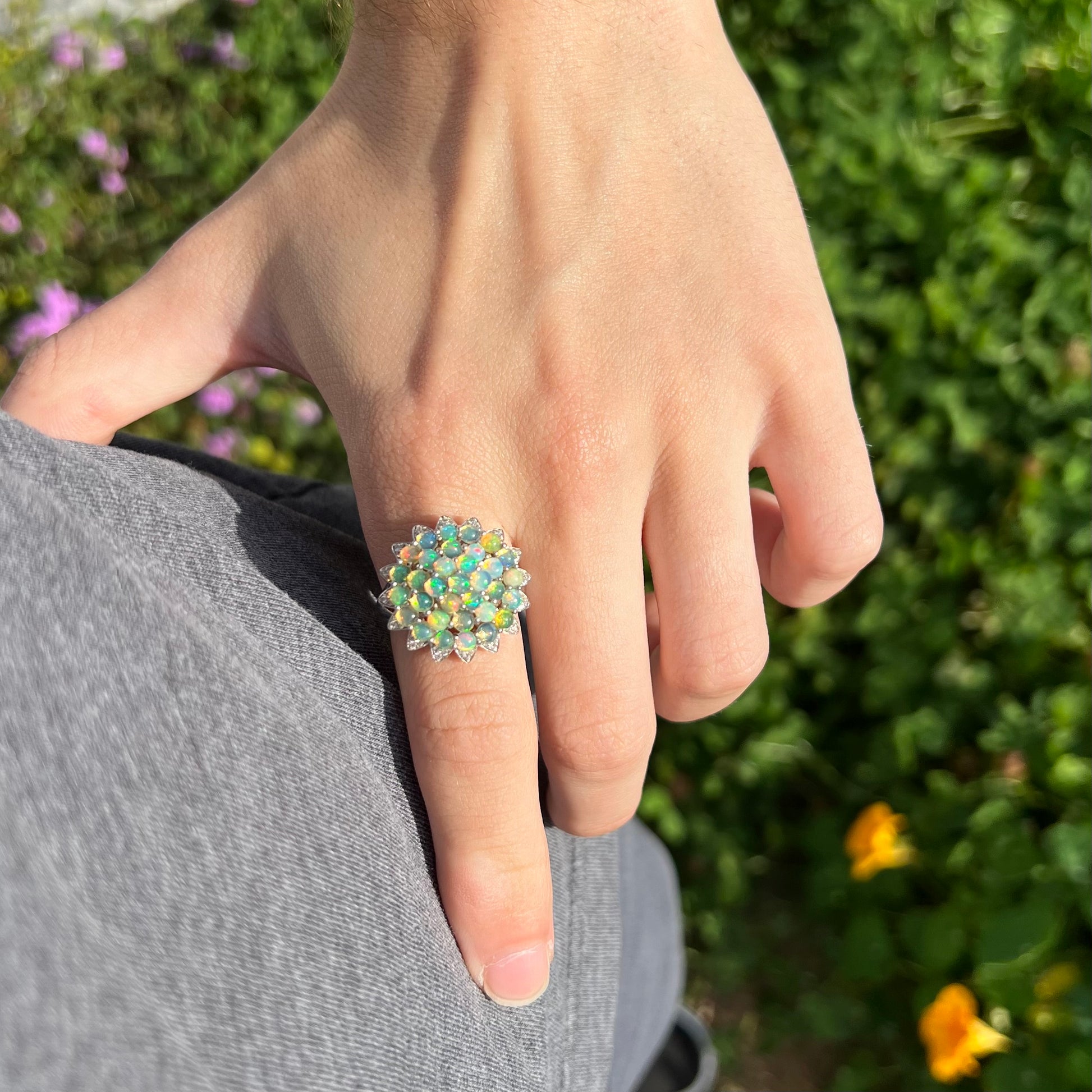 A sterling silver cluster flower ring mounted with 33 round Ethiopian fire opals.