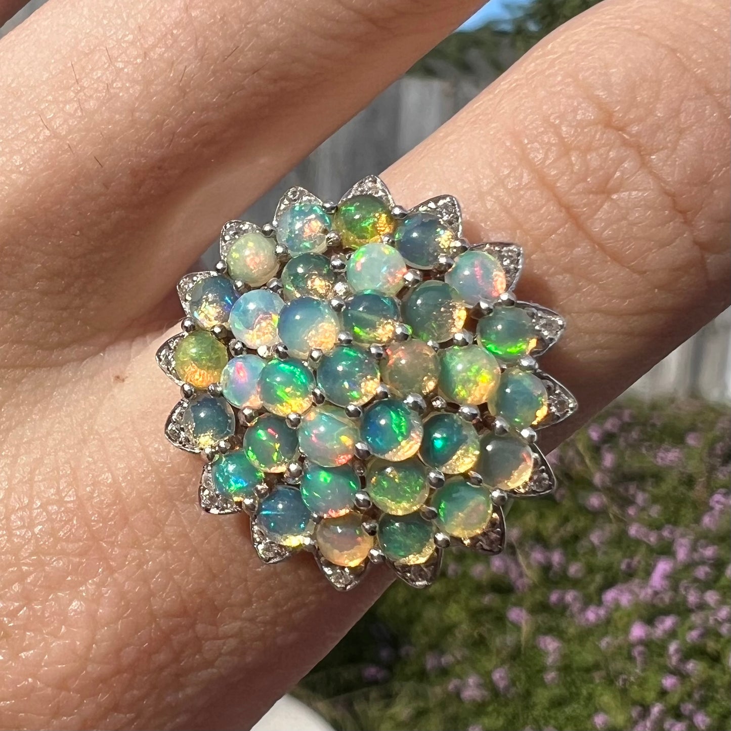 A sterling silver cluster flower ring mounted with 33 round Ethiopian fire opals.