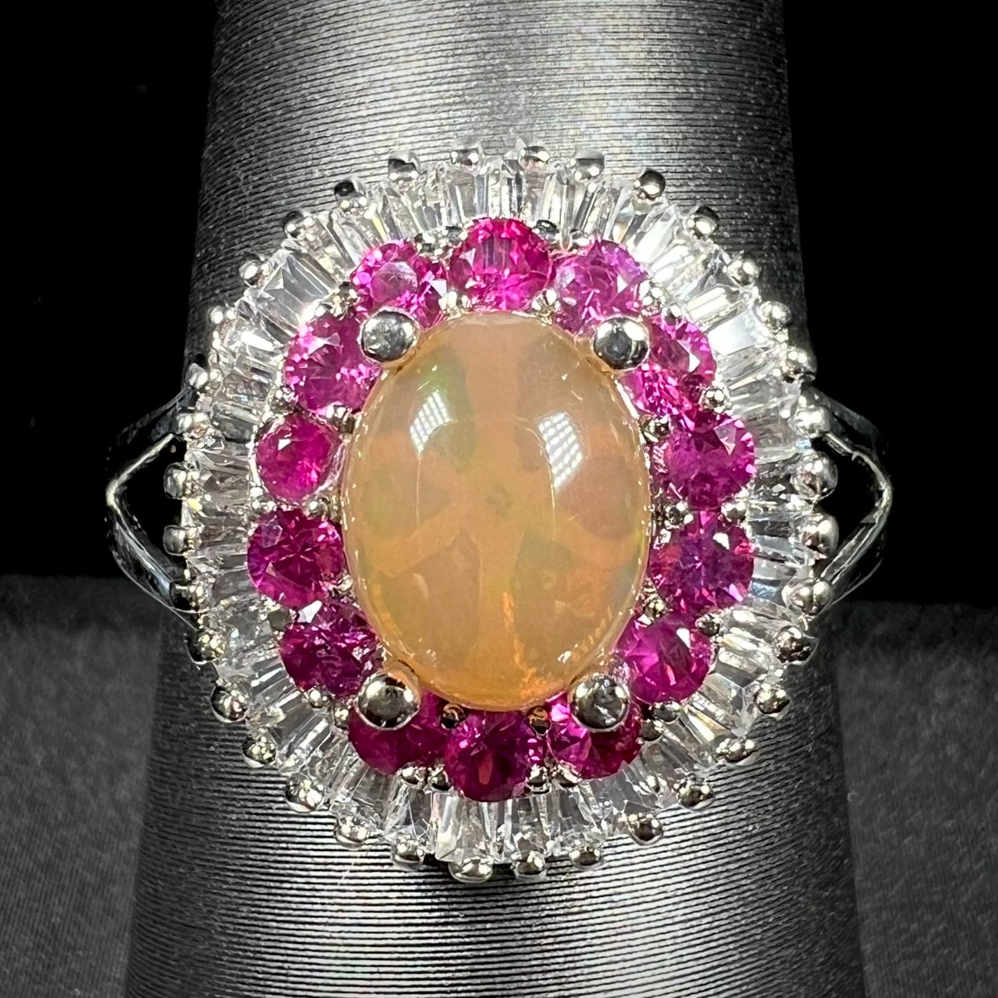 A sterling silver Ethiopian opal ring mounted with a halo of white CZs and another halo of synthetic pink sapphires.