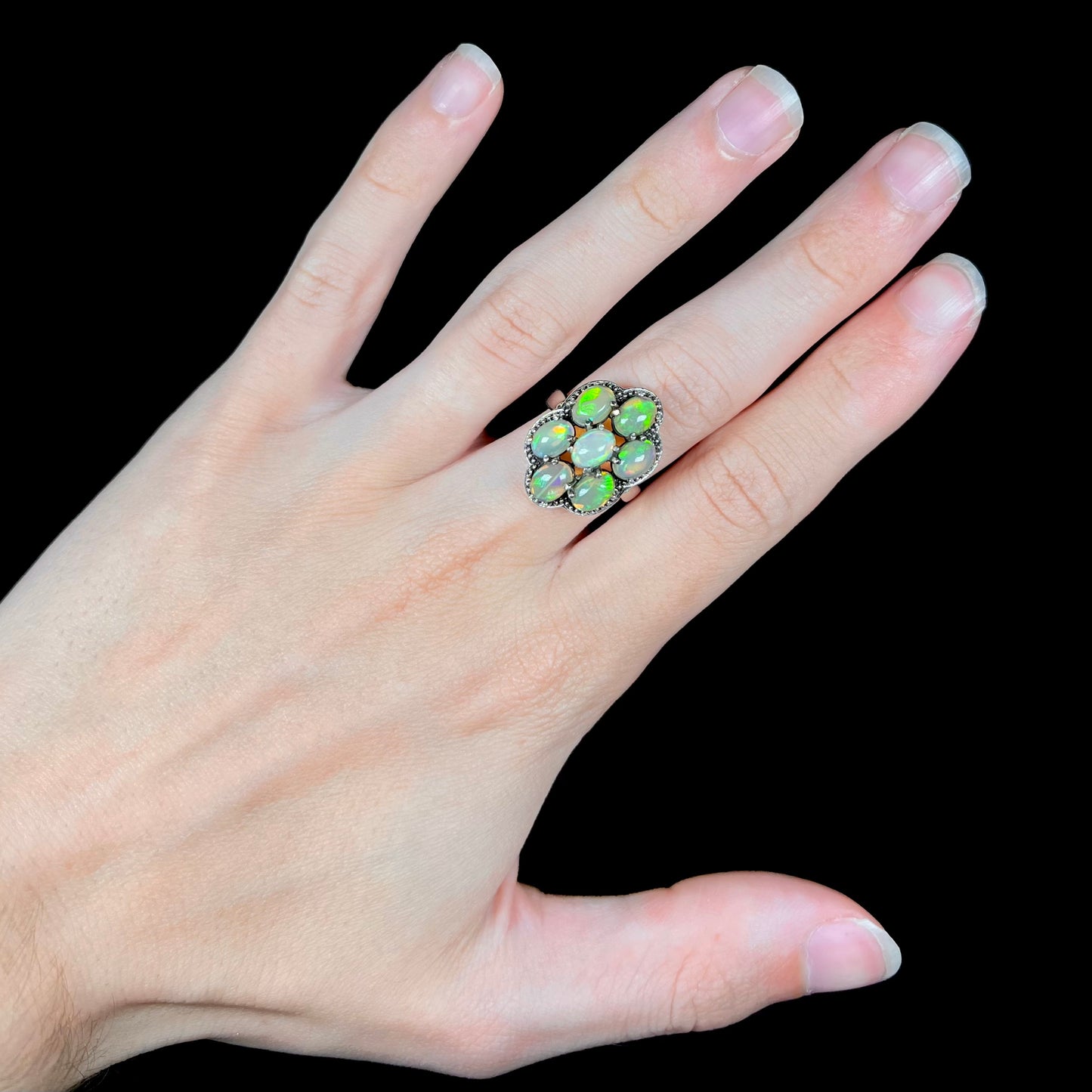 A sterling silver cluster ring prong-set with seven green Ethiopian fire opals.