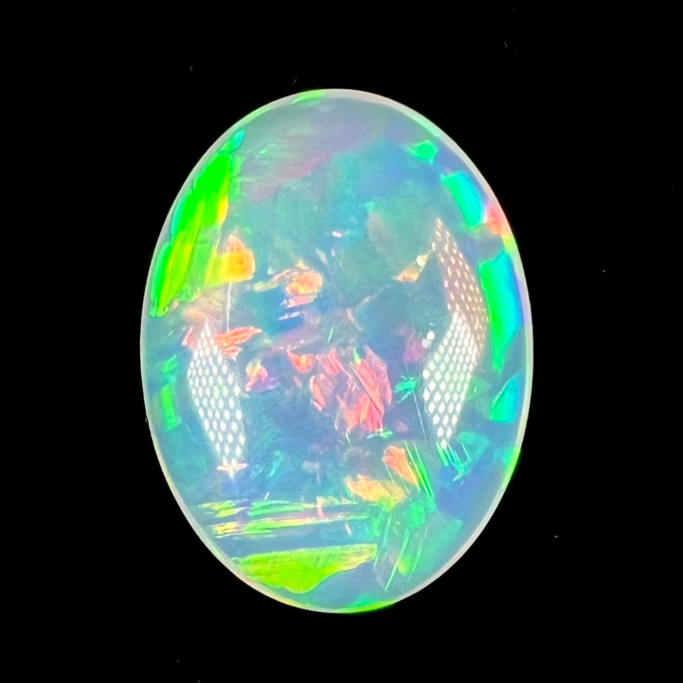 A loose, oval cabochon cut Ethiopian crystal fire opal.  The opal has vivid green, blue, and red colors.