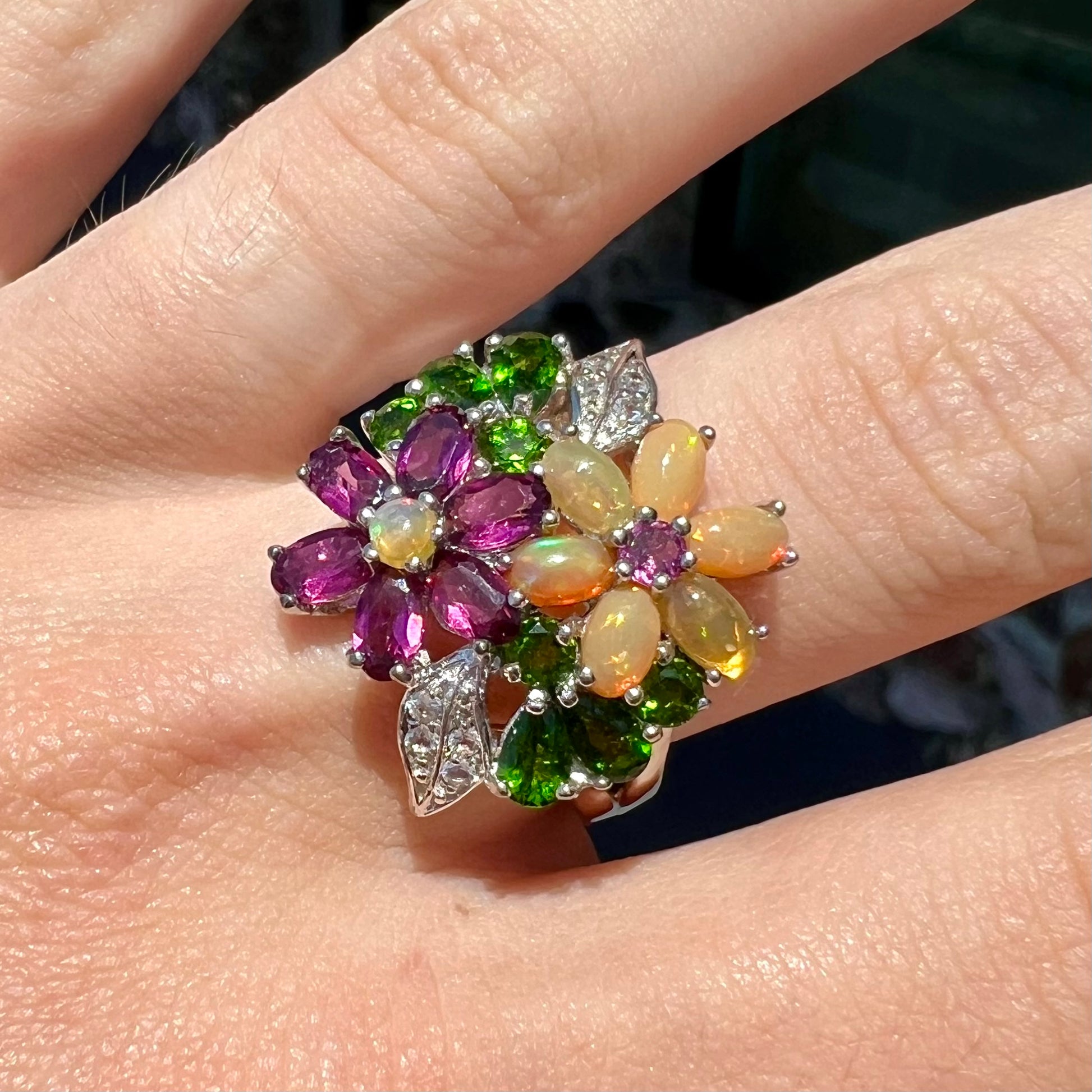 A ladies' gemstone flower design cluster ring set with Ethiopian fire opals, chrome diopsides, rhodolite garnets, and white topaz stones.