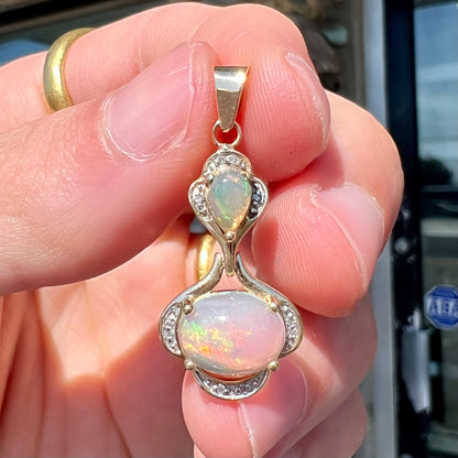 A ladies' yellow gold and diamond accented pendant set with two natural Ethiopian fire opals.