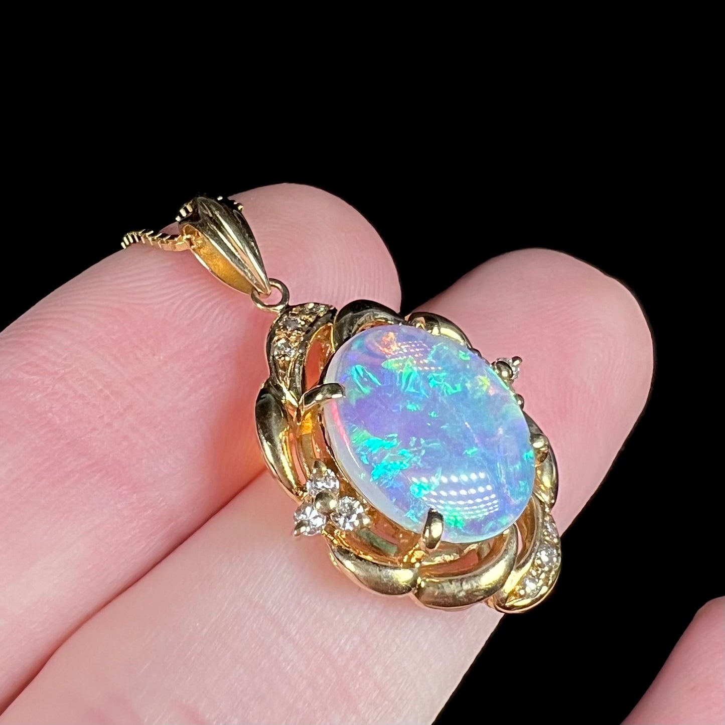 An 18 karat yellow gold diamond-accented necklace mounted with a green and blue Lightning Ridge crystal opal.