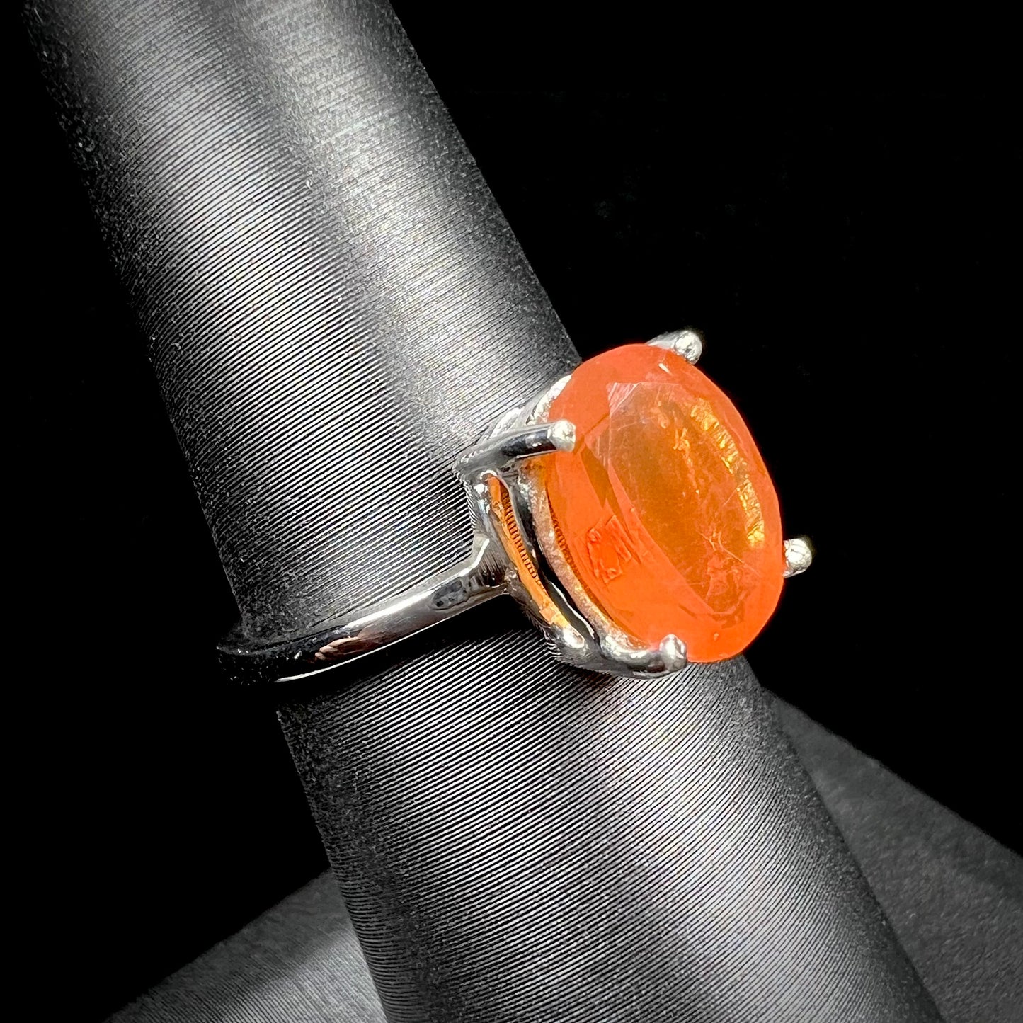 A silver solitaire ring set with a natural, faceted oval cut Mexican fire opal.  The stone is a bright orange color.