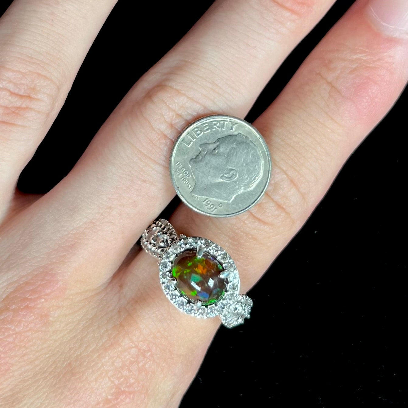 A CZ-accented sterling silver halo ring mounted with a smoked Ethiopian fire opal.  The opal plays green, red, and blue colors.