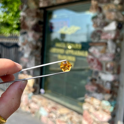 A loose, faceted hexagon cut citrine gem.  The stone is golden yellow color.