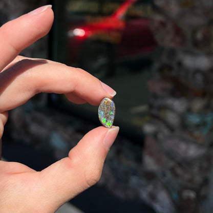 A loose boulder opal stone from Quilpie, Australia.  The opal has bright green and blue flashes.