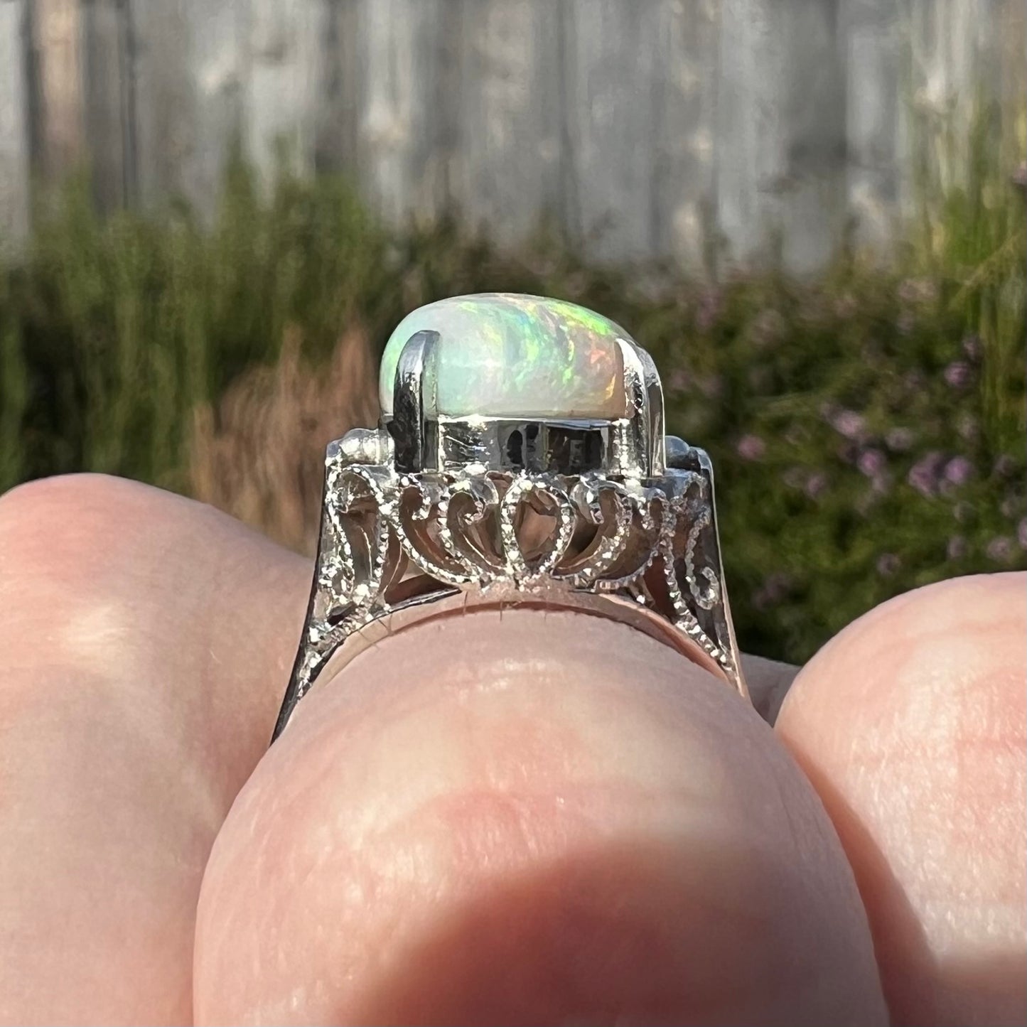 A ladies' Australian opal solitaire engagement ring mounted in platinum.  The opal has green and blue colors.