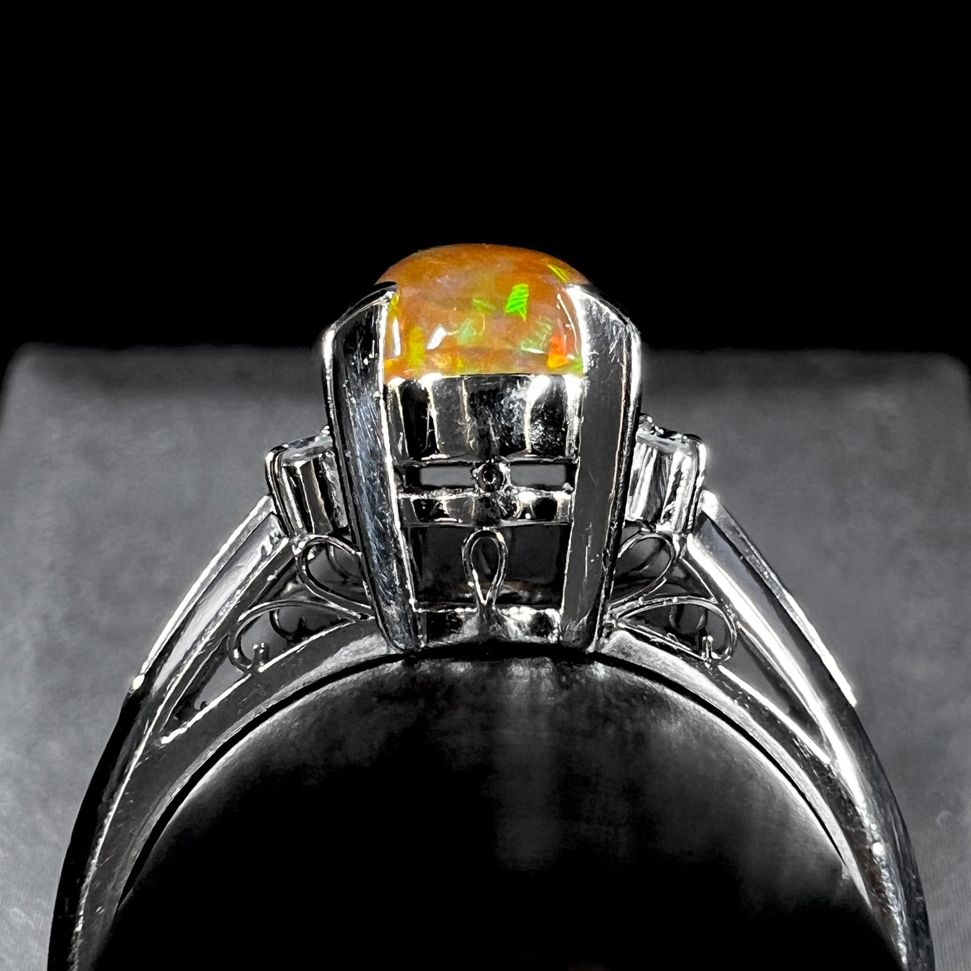 A platinum filigree and diamond-accented Mexican fire opal ring.  The opal is orange with green fire.