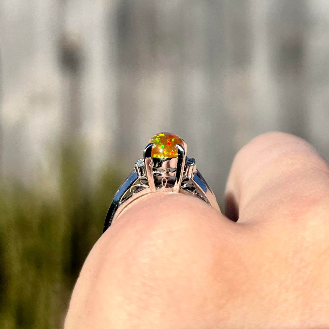 A platinum filigree and diamond-accented Mexican fire opal ring.  The opal is orange with green fire.