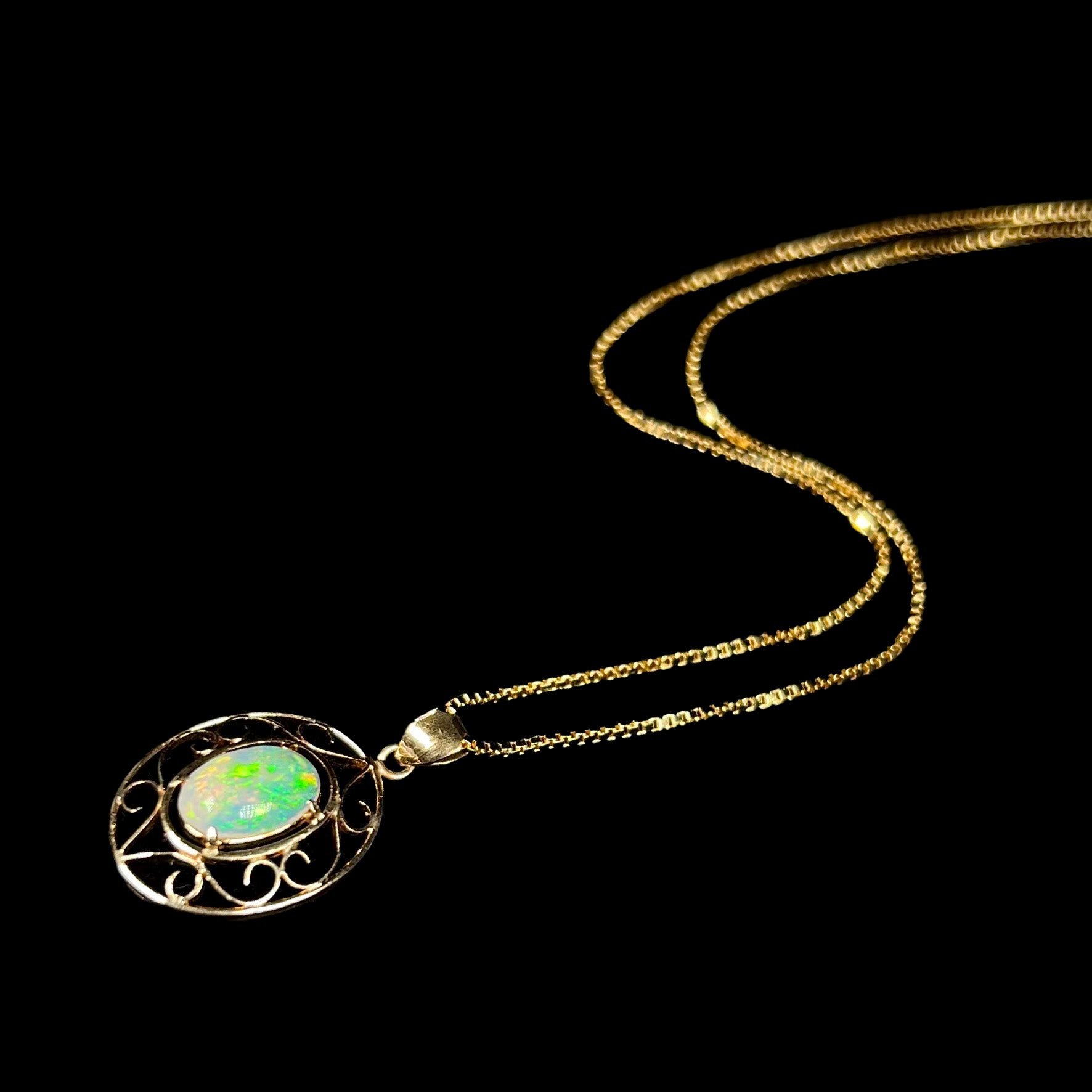 An 18 karat yellow gold filigree opal necklace.  The opal has bright green color play.