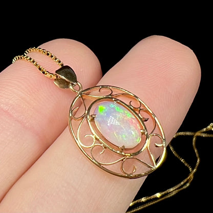 An 18 karat yellow gold filigree opal necklace.  The opal has bright green color play.