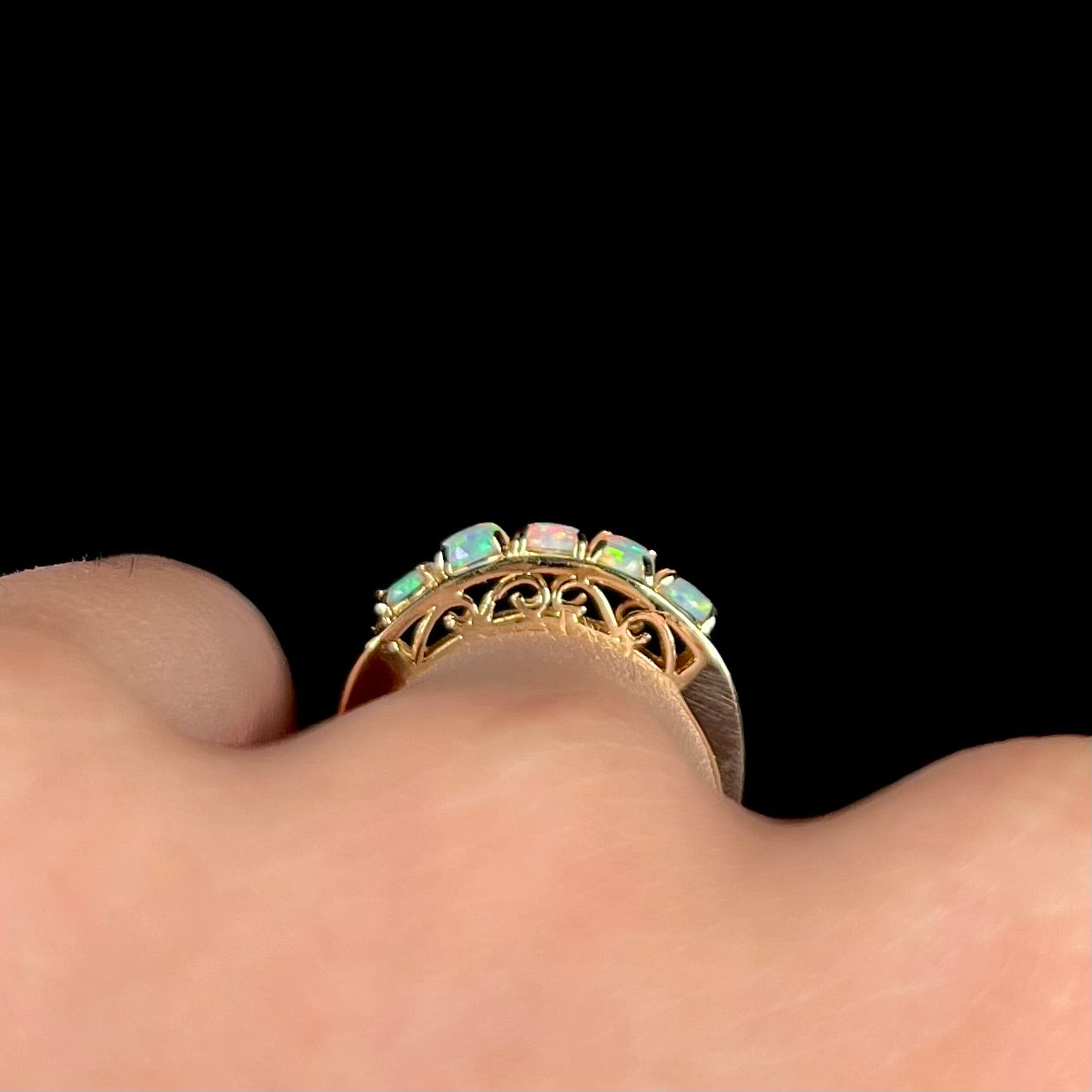 An 18 karat yellow gold line-style filigree ring mounted with five round, cabochon cut Australian crystal opals.