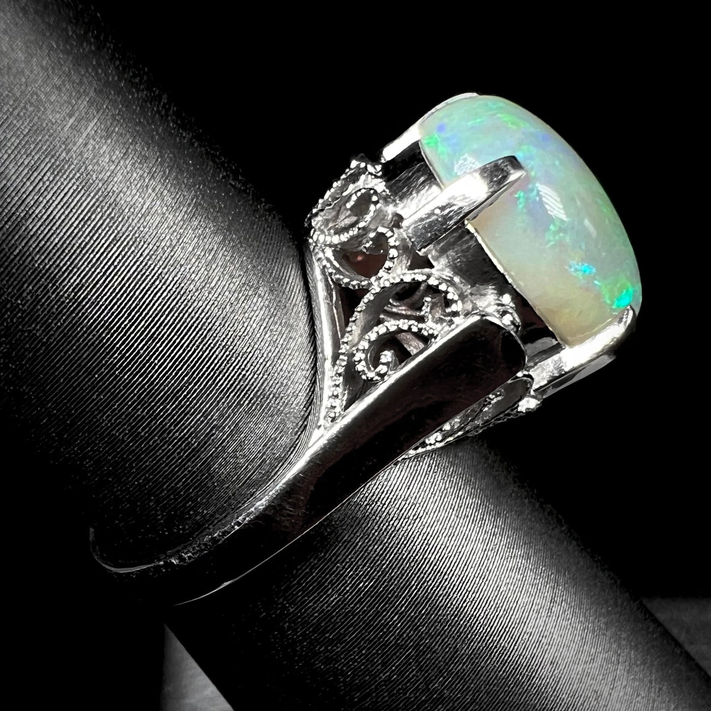 A ladies' Australian opal solitaire engagement ring mounted in platinum.  The opal has green and blue colors.