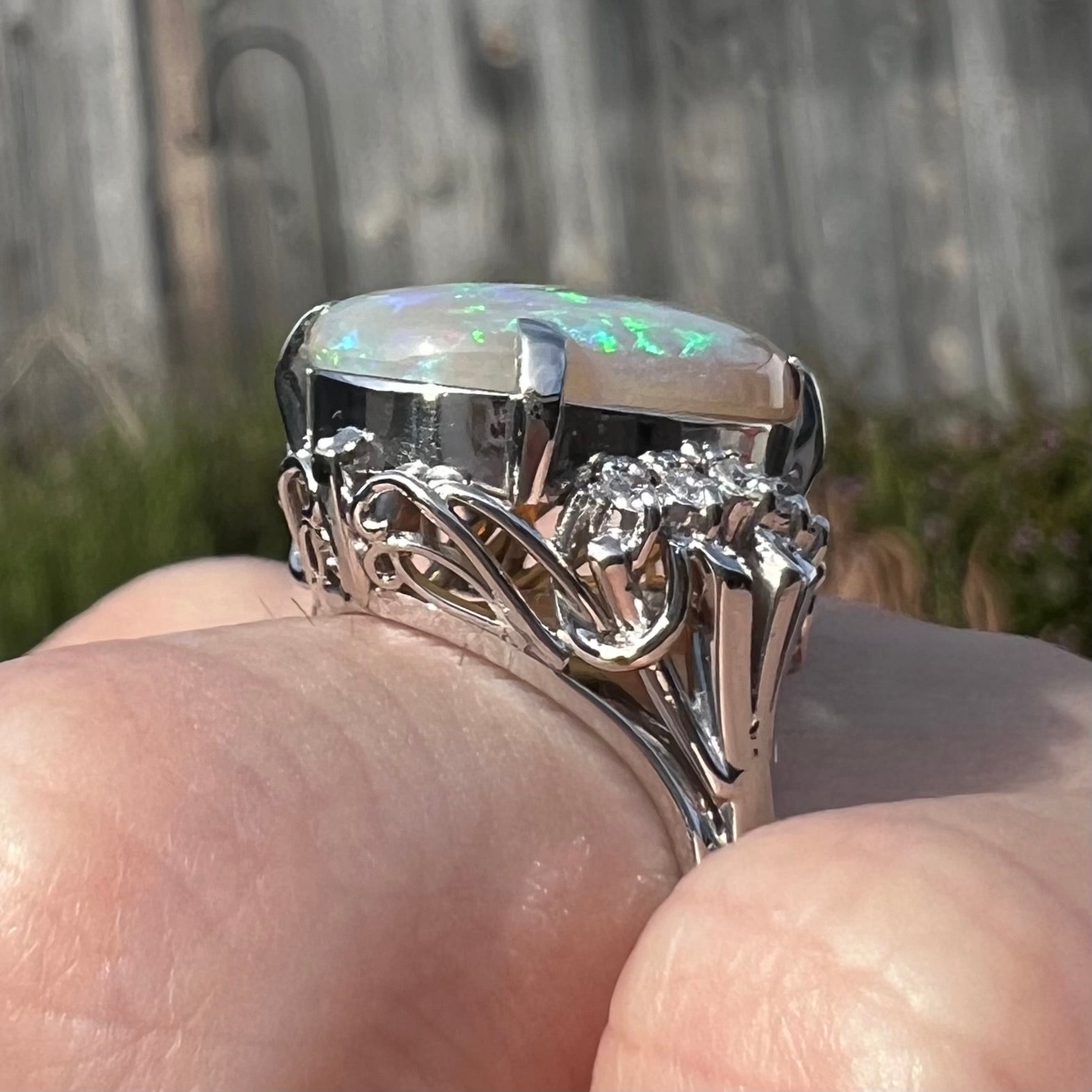 A platinum filigree engagement ring set with a large, green-blue Australian crystal opal.