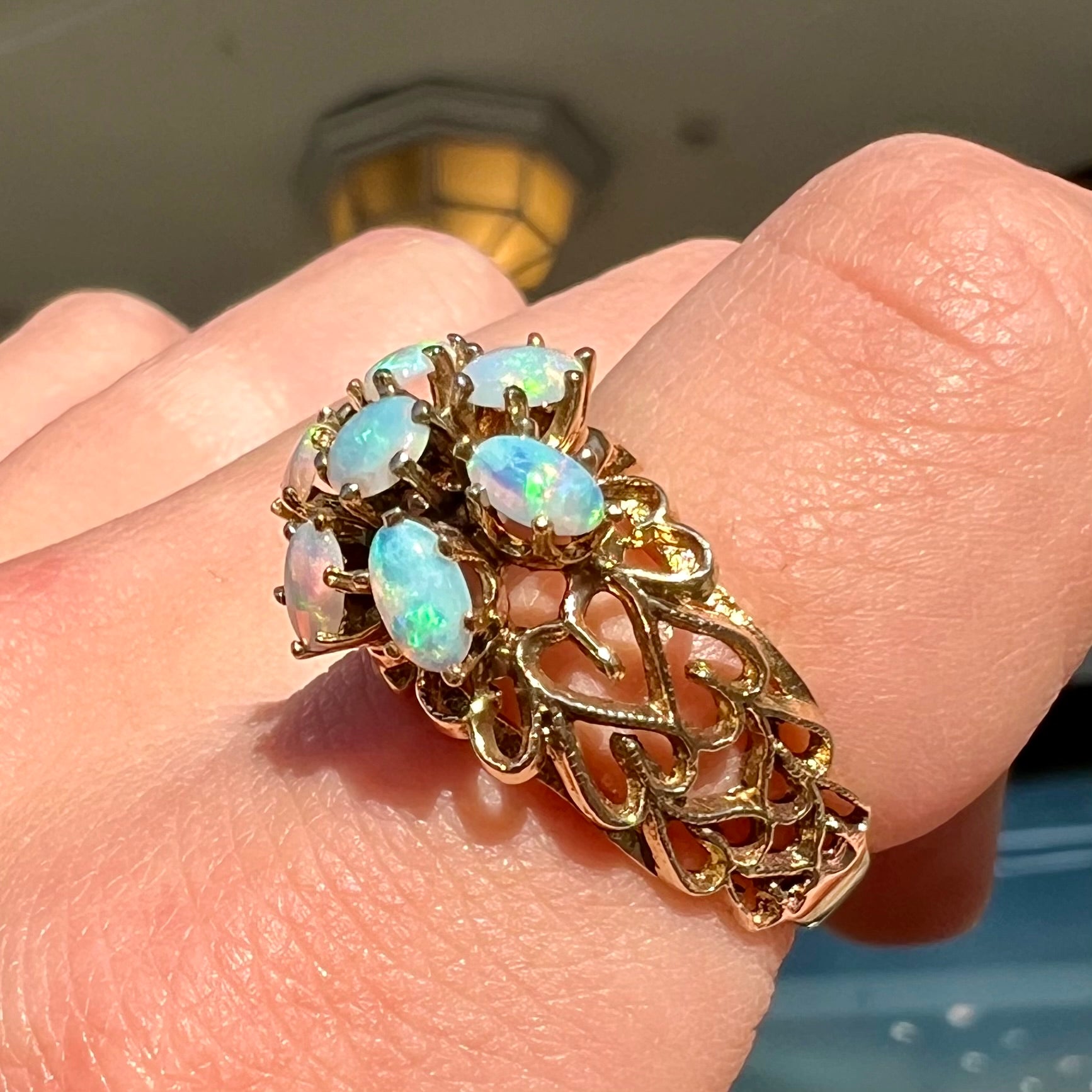 A vintage, 1950's style opal cluster ring cast in yellow gold with a heart shaped filigree design.