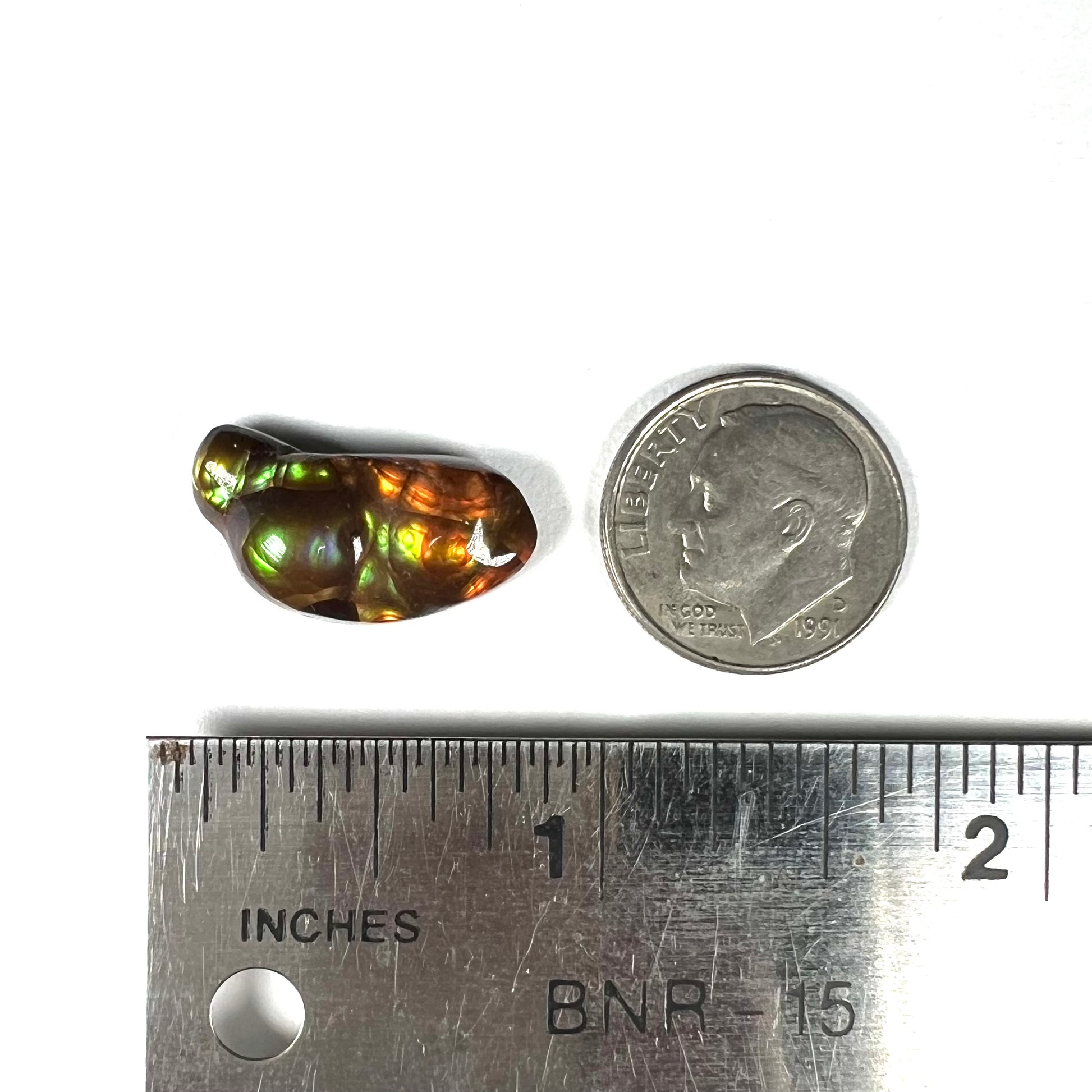 A loose, freeform shaped fire agate stone.  The fire agate has red, orange, and yellow colors on one side, and the other has green and blue colors.