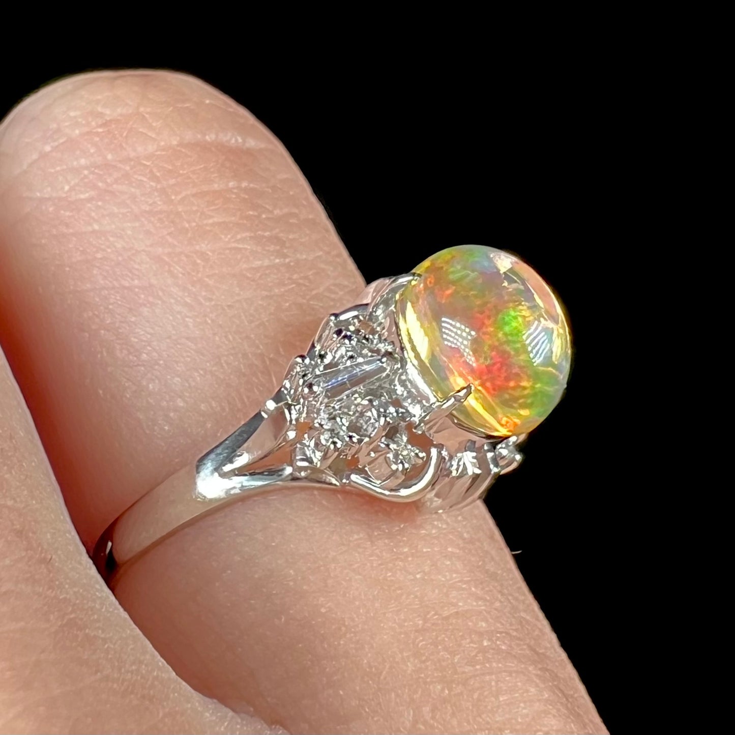 A platinum filigree ring mounted with a high-domed Mexican fire opal and baguette cut diamond accents.