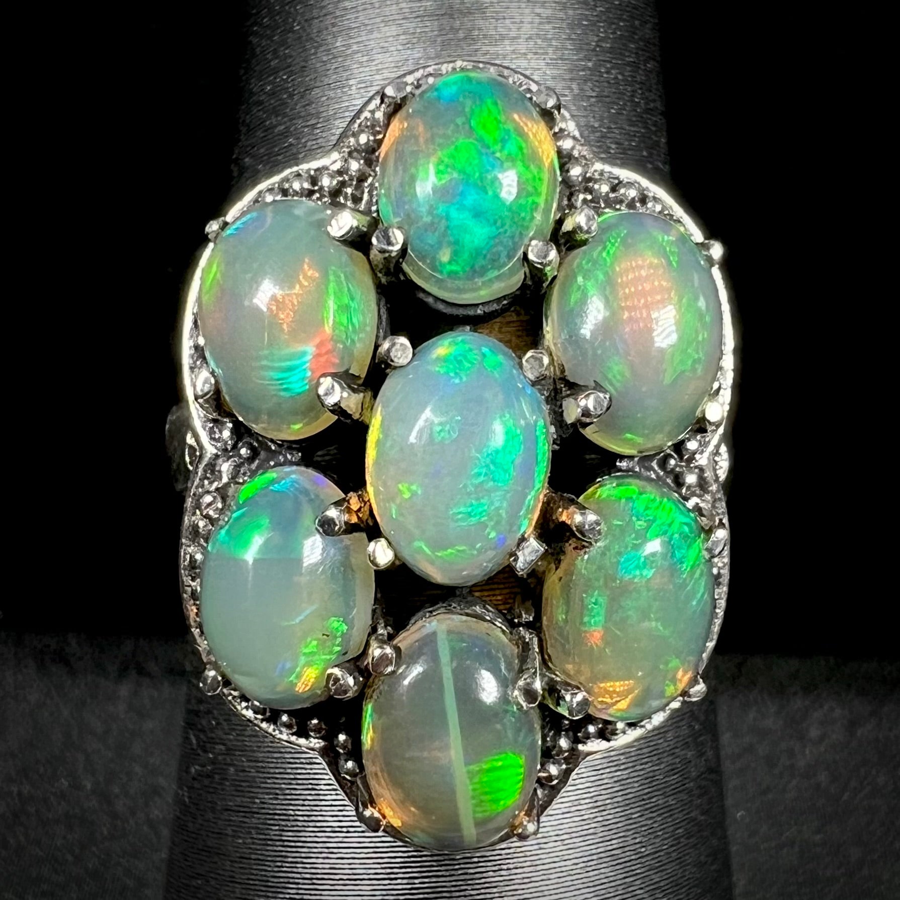 A sterling silver cluster ring prong-set with seven green Ethiopian fire opals.