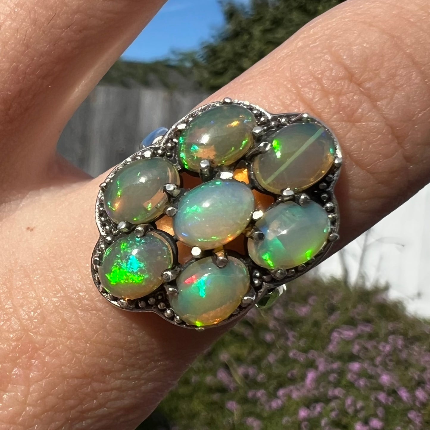 A sterling silver cluster ring prong-set with seven green Ethiopian fire opals.