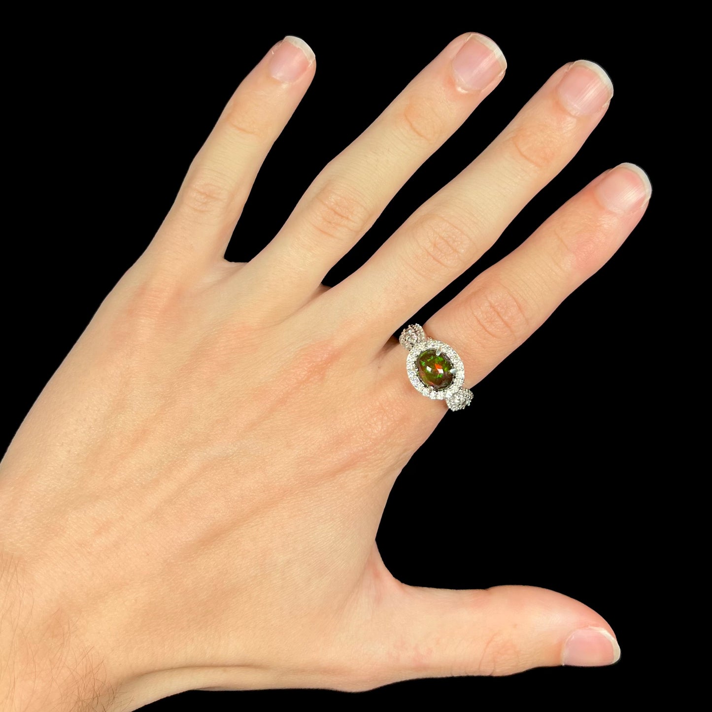 A CZ-accented sterling silver halo ring mounted with a smoked Ethiopian fire opal.  The opal plays green, red, and blue colors.