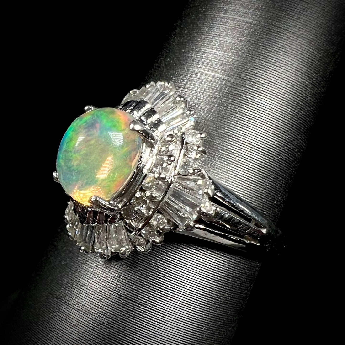 A platinum ring mounted with a Mexican fire opal and baguette cut diamond accents.