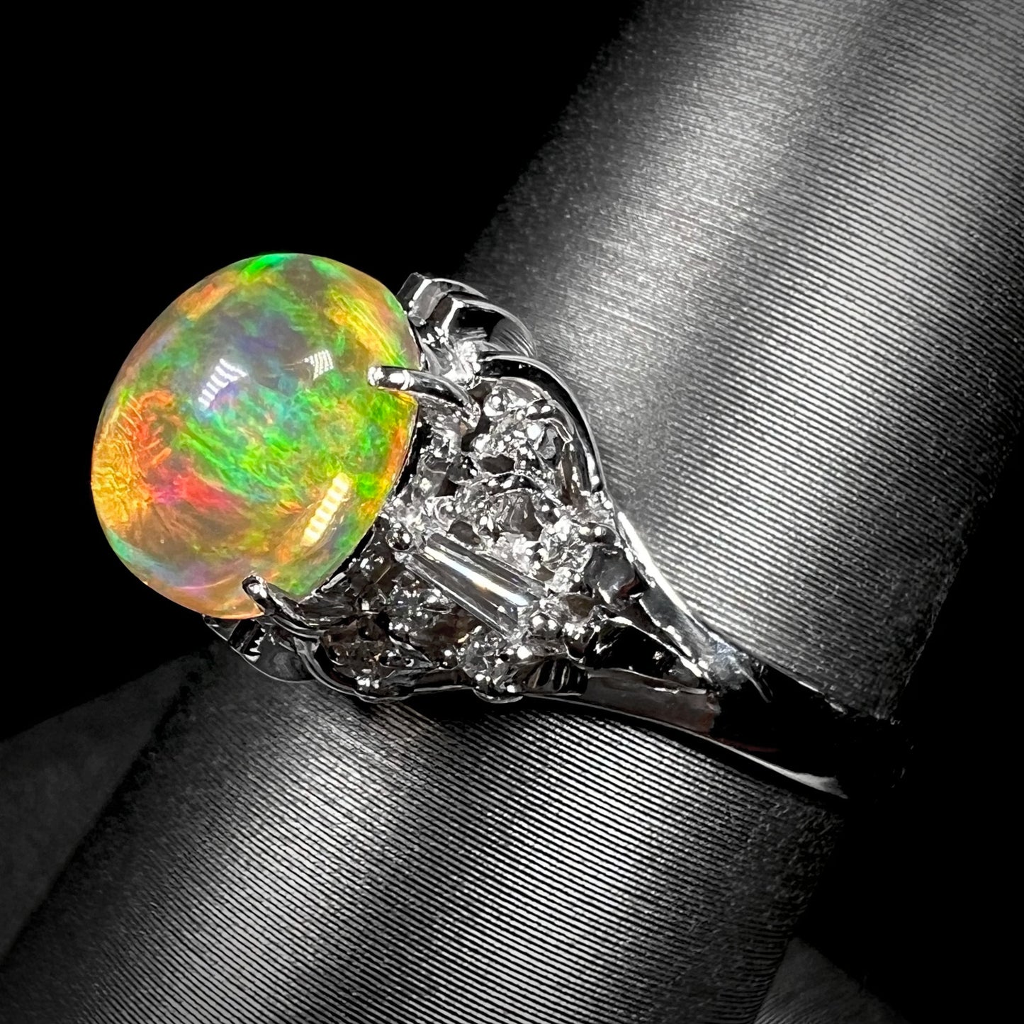 A platinum filigree ring mounted with a high-domed Mexican fire opal and baguette cut diamond accents.