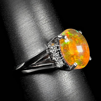 A platinum filigree and diamond-accented Mexican fire opal ring.  The opal is orange with green fire.